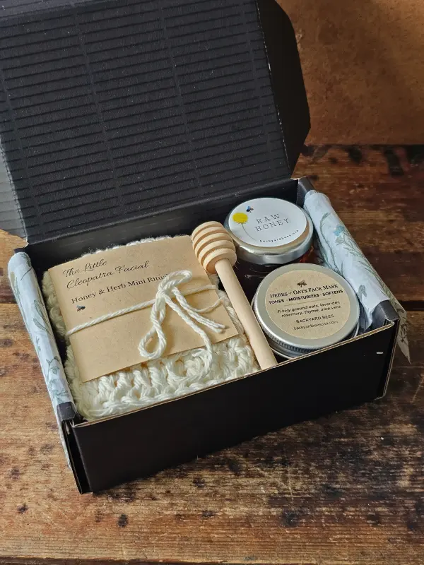Cleopatra Mini gift set arranged inside an open black box with washcloth, face mask, honey, and dipper