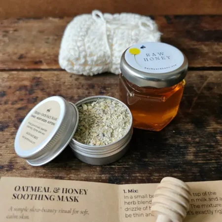 Open oatmeal and honey face mask tin beside the Cleopatra Mini washcloth, honey jar, dipper, and ritual card