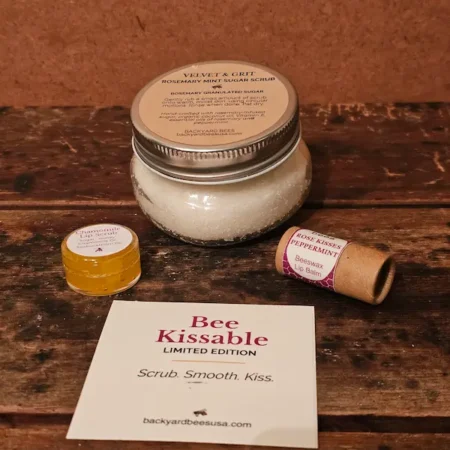 Bee-Kissable-Limited-Edition-Flat-Lay Flat lay of contents of Bee Kissable Gift Box on rustic wood table - Rosemary Mint Sugar Scrub, honey chamomile lip scrub, and Rose Kisses Lip Balm