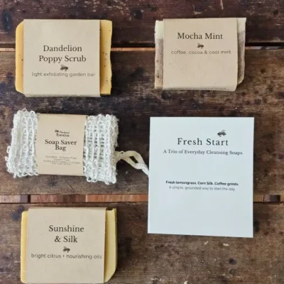 Fresh Start Flat Lay Handmade soap trio including Dandelion Poppy, Mocha Mint, Sunshine & Silk and reusable sisal soap saver bag