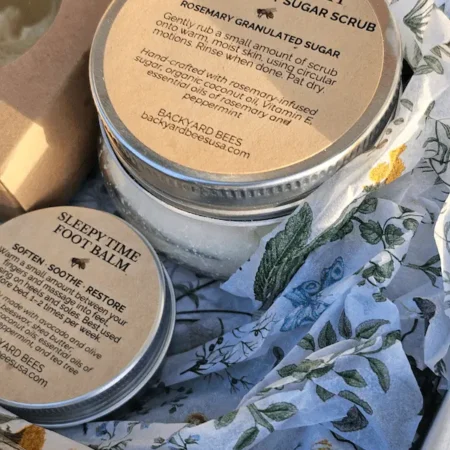 Close-up of rosemary mint body scrub and foot balm in eco-friendly packaging with botanical tissue