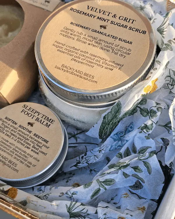 Close-up of rosemary mint body scrub and foot balm in eco-friendly packaging with botanical tissue