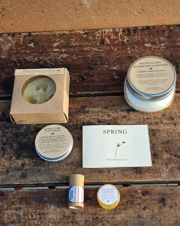 Natural spring skincare gift set with body scrub, foot care, and lip care products arranged on a wooden table