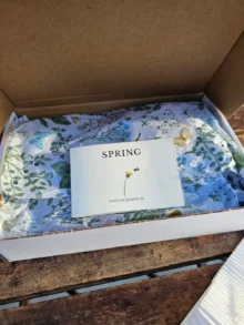 Spring skincare gift set with honey-based body scrub, foot balm, lip balm, and botanical packaging in an open box