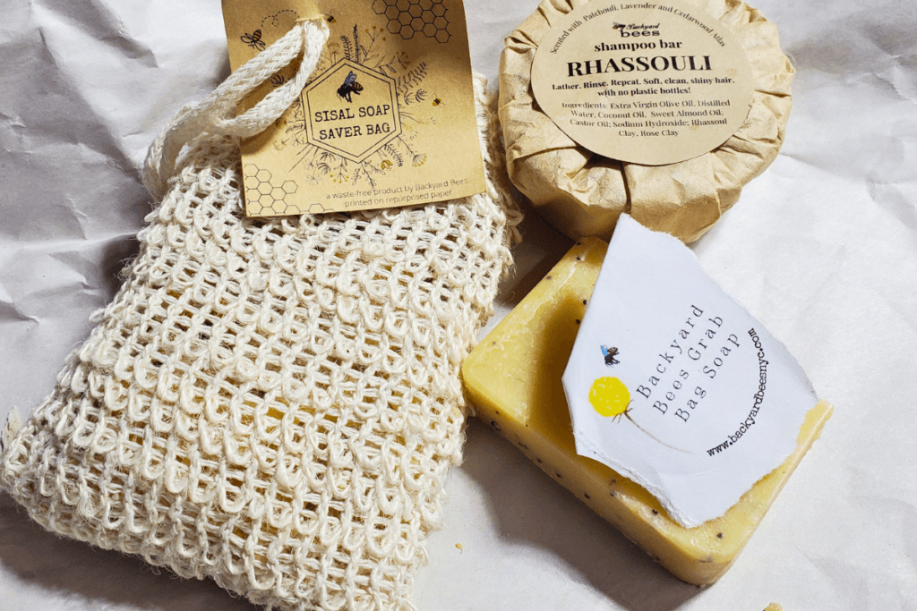a trio of Backyard Bees waste free products including soap saver bag, Rhassouli shampoo bar, and a grab bag soap