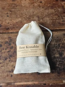 drawstring muslin bag with Bee Kissable beeswax lip balm trio on weathered wood