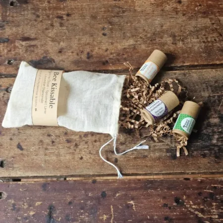 Bee Kissable Trio Open Contents of Bee Kissable Lip Balm Trio spilled out of bag on weathered wood