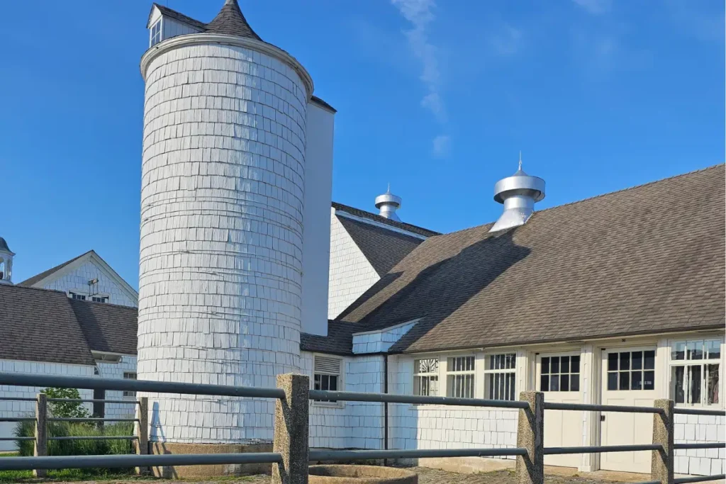 The Hive 8 Restored dairy barns and silo at Caumsett State Park beneath a bright blue summer sky.