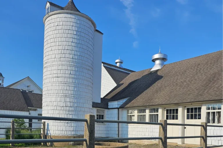 Restored dairy barns and silo at Caumsett State Park beneath a bright blue summer sky.