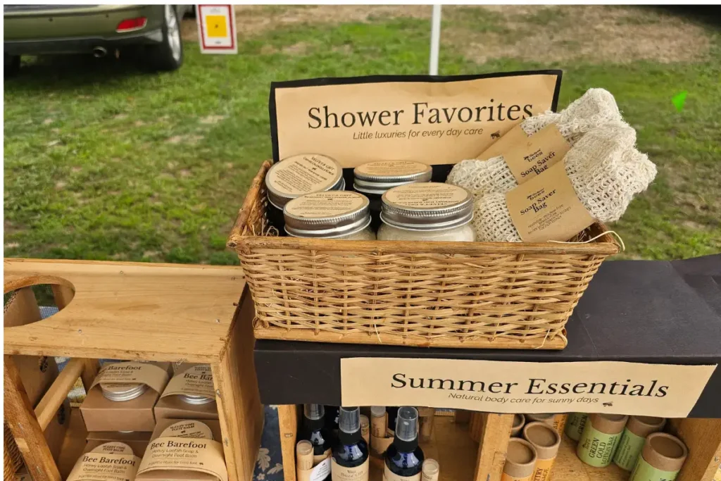 Backyard Bees farmers market display with stacked tea tins and handmade soap saver bags
