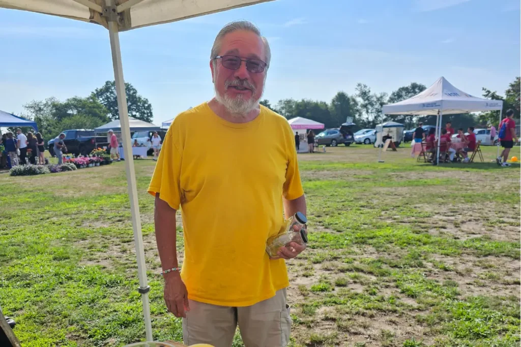Customer John returns empty Backyard Bees honey jars for reuse as part of the market's sustainability efforts.