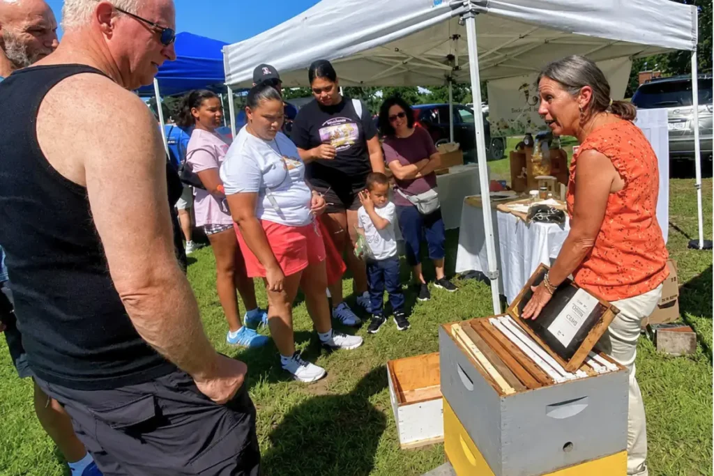 Backyard Bees beekeeper demonstrating an empty hive at the farmers market